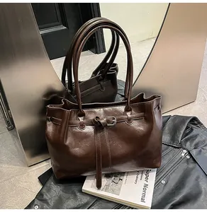 Detailed view of a brown leather shoulder bag with decorative buckle on a leather jacket