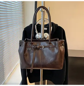 Detailed view of the dark brown leather shoulder bag hanging on a rack.