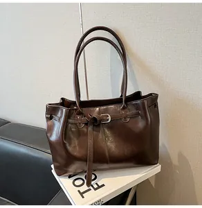 Minimalist large capacity brown glossy leather shoulder bag displayed on a display stand