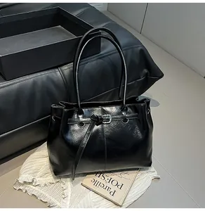 Detail of black minimalist leather tote bag with elegant buckle and long shoulder straps.