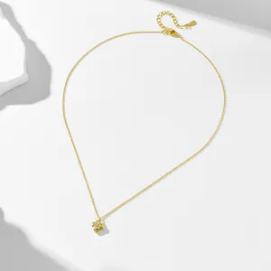 Detail view of a minimalist gold four-leaf clover pendant necklace with sparkling zircons.