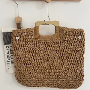 Detailansicht einer handgefertigten Strohtasche mit quadratischem Holzgriff.
