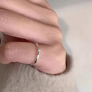 Macro detail of a minimalist 925 sterling silver Mobius ring with a small inset stone