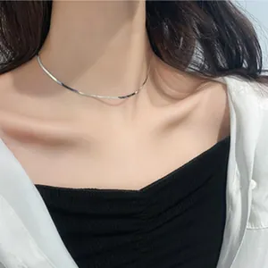 Detail of minimalist 925 sterling silver snake chain necklace on female collarbone