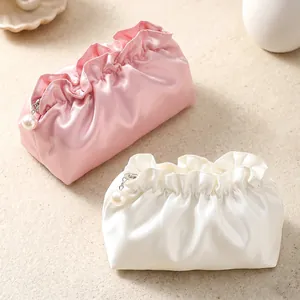 Elegant pink and white ruffled satin cloud cosmetic bags with pearl zipper pulls for travel.