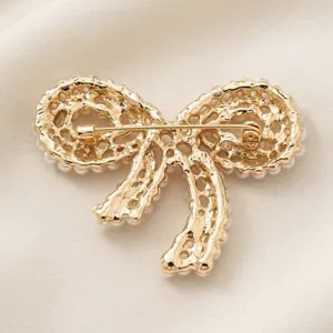Élégante broche nœud ornée de perles dorées pour accessoires de costume de mariage.