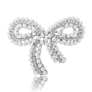 Élégante broche en forme de nœud avec perles blanches et strass brillants sur argent.