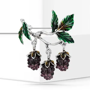 Detailed view of mulberry brooch featuring purple crystals and green enamel leaves