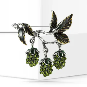 Detail view of a vintage silver mulberry fruit brooch with green crystal accents