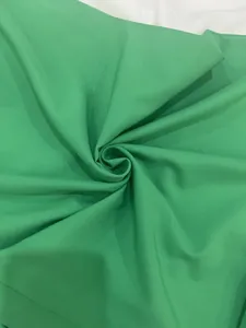 Macro view showing the vibrant green fabric texture and drape of a fashion wide-leg jumpsuit