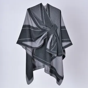 Dettaglio di uno scialle poncho grigio con spacco laterale e motivi geometrici a pois