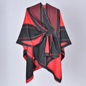Dettaglio dello scialle poncho con motivo geometrico rosso e nero e chiusura laterale