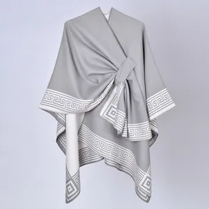 Dettaglio dello scialle poncho grigio da donna con bordi a meandro e chiusura laterale