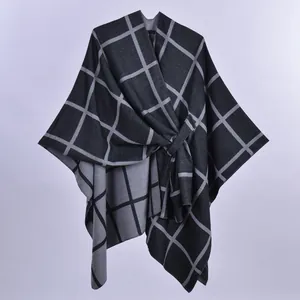 Vista dettagliata della mantella poncho grigia a quadri con elegante nodo laterale e spacco.