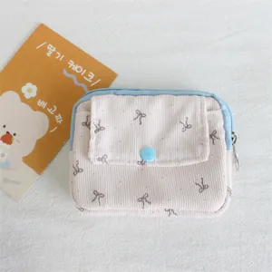 Detailed close-up of a pink corduroy pouch with bow print and blue snap button flap
