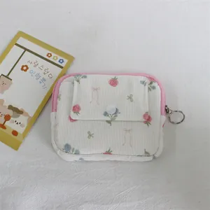 Close-up of a floral print corduroy coin purse with a pink zipper and front flap pocket.