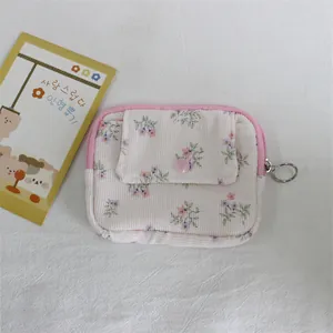 Detail of corduroy floral coin purse with pink snap flap and zipper ring on white fabric.
