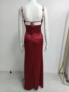 Vue arrière détaillée d'une robe longue en satin rouge avec dos nu et fleurs brodées.