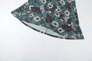 Detailopname van de bloemenprint fishtail zoom op een groene jurk met mouwen