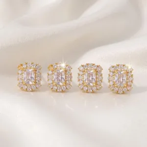 Elegant gold-tone geometric stud earrings featuring sparkling crystals on white silk background.