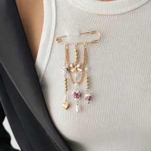 Elegant gold-tone safety pin brooch with hanging heart, bow, and floral bead charms.