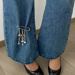 Elegant heart and bow charm safety pin brooch showcased on blue denim pants for women