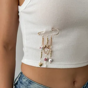 Sweet gold heart and bow beaded safety pin brooch accessory on a white ribbed tank top