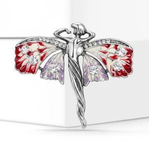 Close-up of vintage silver fairy brooch with red enamel wings and crystal accents