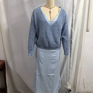 Detail shot of a blue knit sweater layered over a light blue satin slip dress set.