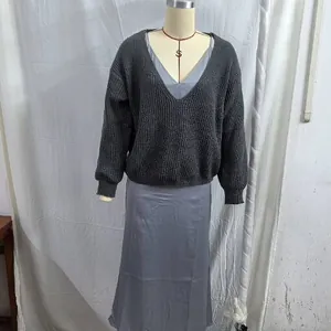 Detailed view of a fashionable women's grey V-neck knit sweater and satin slip dress