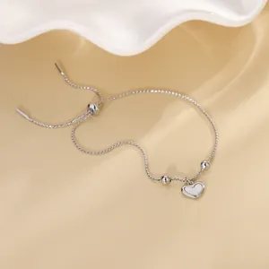 Detailed view of an adjustable silver bracelet featuring a shell heart pendant and beads.
