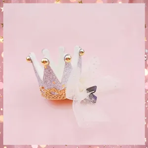 Detailed view of a sparkly pink glitter crown hair clip featuring a delicate white mesh tulle bow.