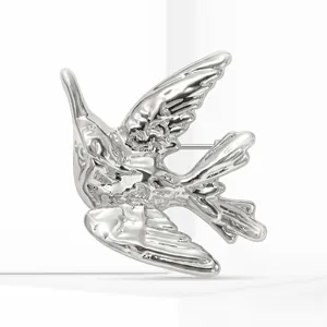 Gros plan d'une broche colibri en alliage argenté brillant avec texture métal liquide.