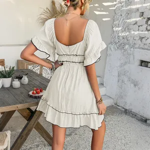 Elegant off-white vacation dress with black ruffled edges and open back design.