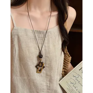 Dettaglio di una lunga collana vintage con ciondoli geometrici quadrati intrecciati