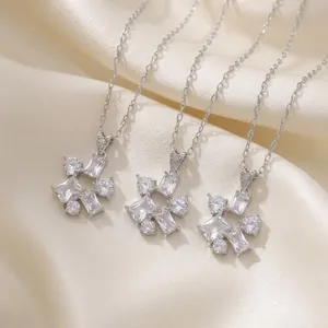 Close-up of three elegant geometric zircon necklaces on soft silk fabric background.