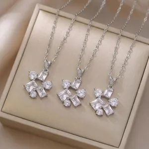 Close-up of geometric zircon necklaces on a beige jewelry box for detailed texture view.