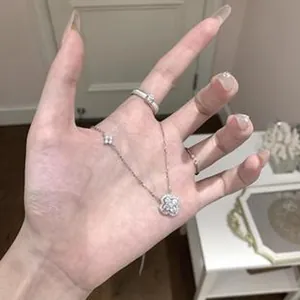 Detailaufnahme einer luxuriösen, funkelnden Halskette mit Kleeblatt-Anhänger in der Hand