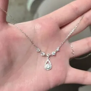 Detailansicht einer eleganten Tropfenhalskette mit funkelnden Zirkonia-Steinen in der Hand