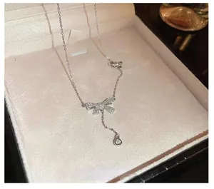 Detail view of sterling silver bow pendant necklace with dangling round zircon stone