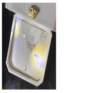 Detailed view of S925 silver bow necklace with zircon tassel in white box.
