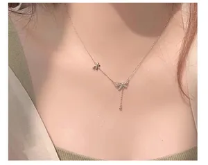 Close-up view of a delicate S925 silver bow necklace with zircon tassel worn on the neck
