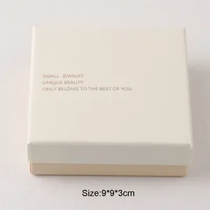 Detalle de caja de regalo de joyería beige minimalista con cita y tamaño impresos