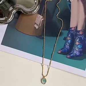 Collana minimalista a grani dorati con ciondolo ovale in pietra occhio di gatto