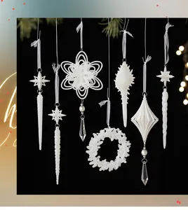 Assorted white glittery Christmas tree ornaments hanging against a black background