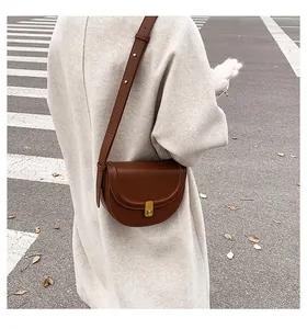 Elegant brown retro saddle crossbody bag worn by a model in a light beige winter coat