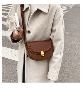 Chic brown saddle bag shown on-body with a light wool coat for a very trendy look