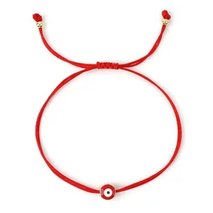 Detail view of handmade woven red string lucky bracelet with red evil eye charm