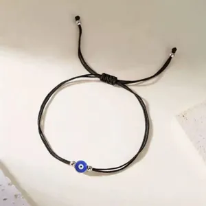 Minimalist handmade woven Evil Eye charm bracelet with an adjustable black string cord