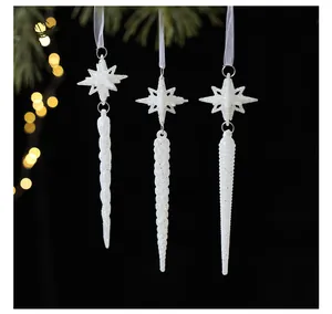 Close-up of white frosted star and icicle Christmas tree ornaments against dark background.